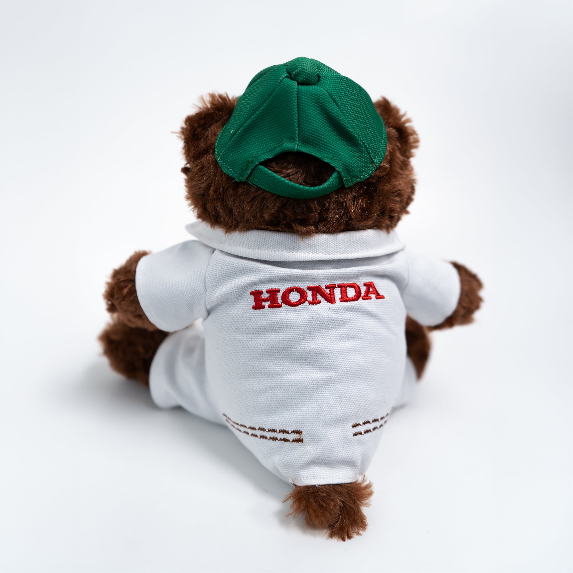 Plush bear wearing a white shirt with 'Honda' logo and green cap on a white background